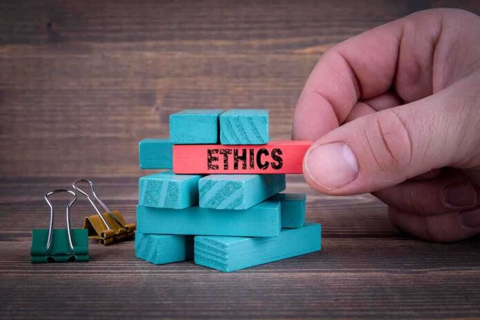 1108182914 featured image Hand holding red block labeled "ETHICS" above blue blocks.