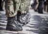 Soldiers in uniform and boots standing in formation.