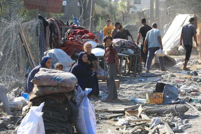 2499606465 featured image People in makeshift camp with tents and belongings.