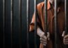 Person in orange uniform behind prison bars