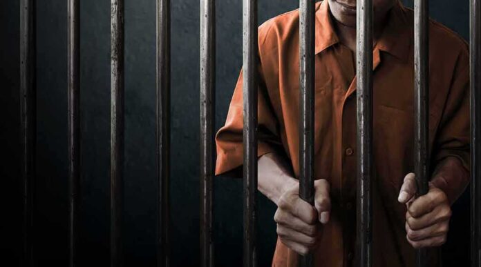 744470836 featured image Person in orange uniform behind prison bars