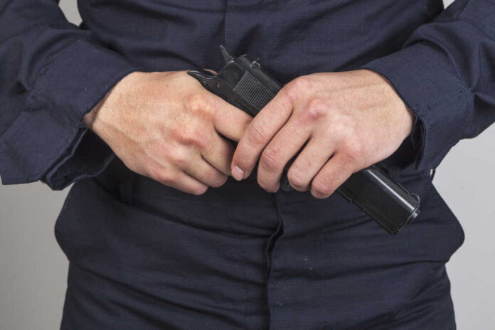 141186946 featured image Person in dark clothing holding a handgun
