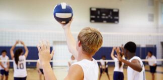 Players about to serve a volleyball in gym