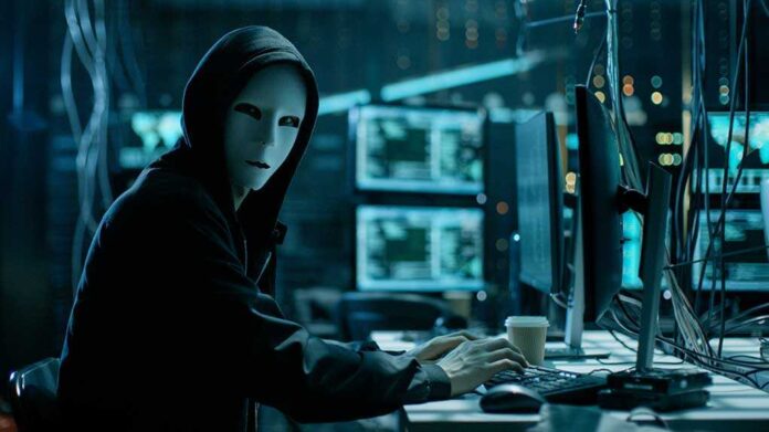 680078920 featured image Person wearing mask and hoodie at computer desk.