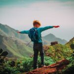 US Rates CRASH—Vance Family Sounds Alarm Child with backpack stands on mountain arms outstretched