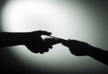 Silhouette of hands exchanging money in dim light