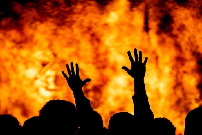 1746475793 featured image Silhouetted hands raised against a fiery background.
