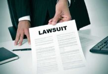 Person holding a document titled LAWSUIT in office