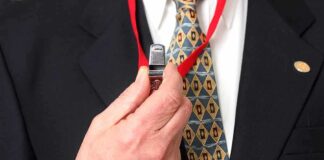 Person holding a whistle on a red lanyard