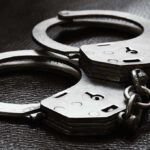 Close-up of metal handcuffs on a dark surface