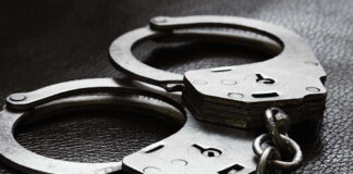 Close-up of metal handcuffs on a dark surface