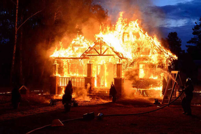 569622439 House engulfed in flames with firefighters present