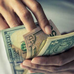 Person holding multiple dollar bills