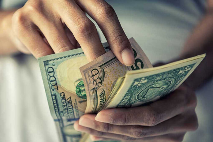 794159299 Person holding multiple dollar bills