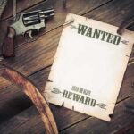 A vintage wanted poster alongside a revolver and rope on a wooden table
