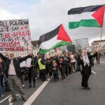 Crowd of protesters holding Palestinian flags and signs during a demonstration