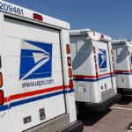 Row of USPS mail delivery trucks parked