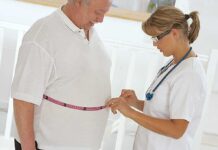 A healthcare professional measuring a patient's waist with a tape measure
