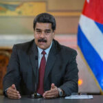 Trump DESTROYS Venezuelan Boats — Maduro RAGES! Man speaking at podium with Cuban flag in background.