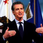 Californias RADICAL NEW BILL – Newsom Decision Looms Man speaking with flags in the background