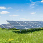 $2.2B Green Energy DISASTER – Failed Experiment! Solar panels in a grassy field under blue sky.