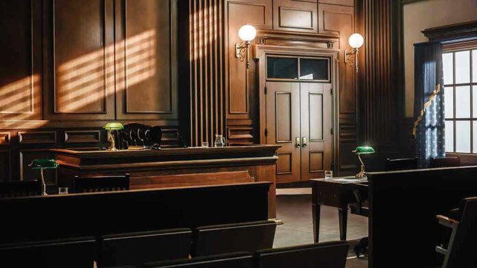 Empty courtroom with wooden interior and green lamps.