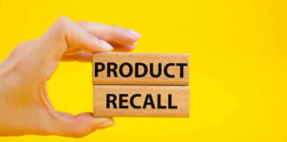 Hand holding Product Recall blocks on yellow background.