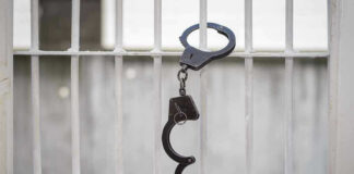 Handcuffs hanging on a barred window.