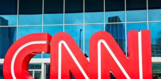 Large red CNN logo in front of a glass building