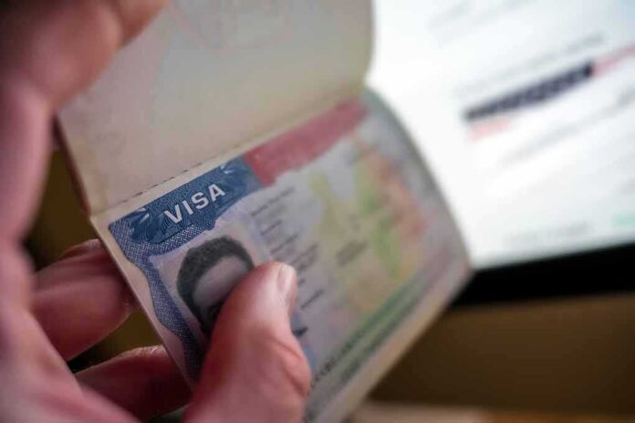 A hand holding an open passport displaying a visa page
