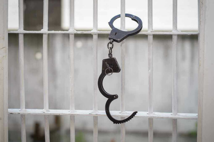 Handcuffs hanging on a barred window.