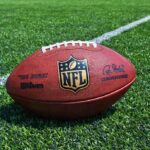 An NFL football resting on a green grass field