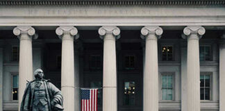 US Treasury Department building with statue and flag.