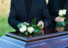 American ICON Dead At 86 After Health Emergency People placing white roses on a casket.