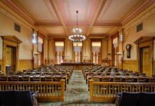 Interior view of a historic courtroom with wooden furnishings and chandeliers