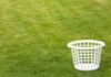 An empty white laundry basket placed on green grass