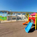 Two Gunman OPEN Fire On Children’s Playground! Colorful playground slide in front of a building.