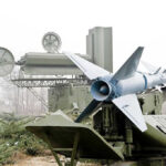Military missile launcher with radar systems in a foggy field.