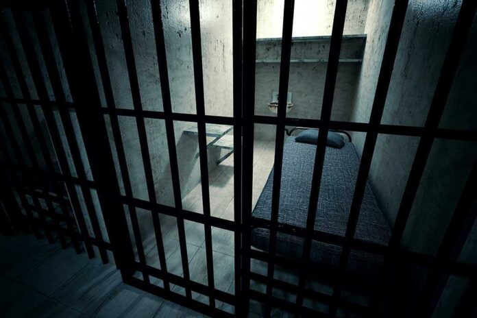 Interior view of a prison cell with a bed and metal bars