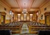 Interior view of a historic courtroom with wooden furnishings and chandeliers