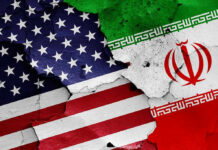 Iran SPEEDS UP Executions of Political Prisoners! Cracked American and Iranian flags painted on a wall.