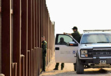 Trump SEPARATES Kids Despite Court-Order Border patrol agents near a tall metal fence.