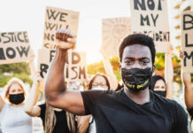 Black Panthers Party STORM Courthouse During Trial! Protester raises fist, wears mask, signs in background.