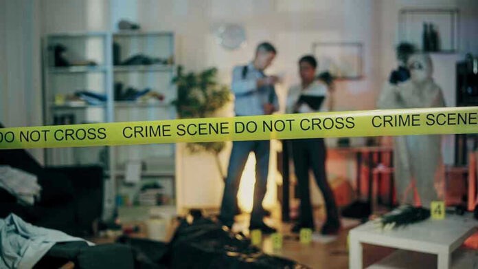 2386626691 Crime scene with tape and investigators examining evidence.