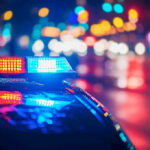 Officer ARRESTED – Badge Turned Weapon! Police car with flashing lights at night.