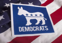 Dem Candidate PULLS Gun In Office – Entire Staff SHOOK! Democrats logo on American flag background