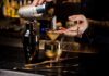 Bartender pouring a cocktail through a strainer into a gold cup