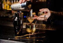 Bartender Found DISMEMBERED – Horror Couple ARRESTED! Bartender pouring a cocktail through a strainer into a gold cup