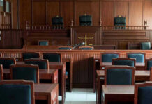 Serial Rapist CAUGHT – After 20 Years! Empty courtroom with wooden furnishings and judges bench.
