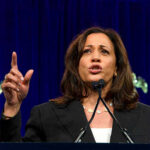 Kamala Makes Desperate Move in Pathetic 2028 Plan Woman speaking passionately at a podium, gesturing upward.